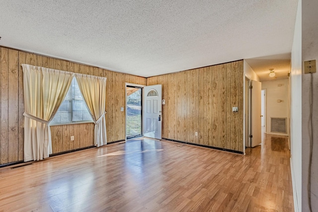 empty room with visible vents, a textured ceiling, and wood finished floors