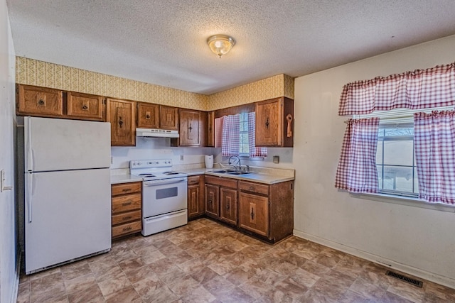 kitchen with white appliances, visible vents, light countertops, under cabinet range hood, and a sink