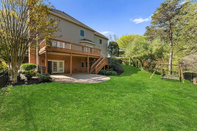 rear view of property featuring french doors, a wooden deck, a fenced backyard, a yard, and a patio area