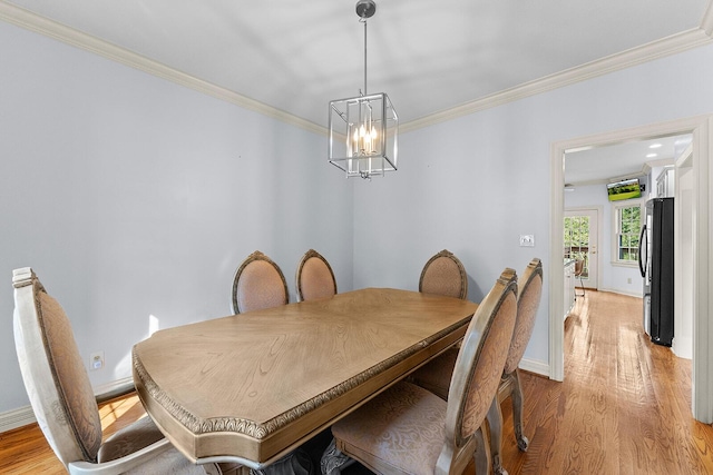dining space featuring light wood-style floors, crown molding, baseboards, and an inviting chandelier