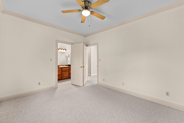 unfurnished bedroom featuring a sink, ensuite bathroom, light colored carpet, crown molding, and baseboards