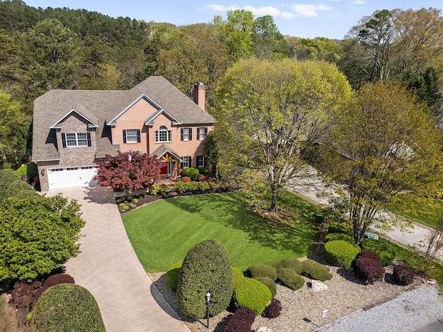 colonial inspired home featuring a chimney, driveway, a front lawn, and a garage