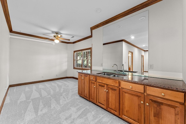 kitchen with a ceiling fan, brown cabinets, ornamental molding, and a sink