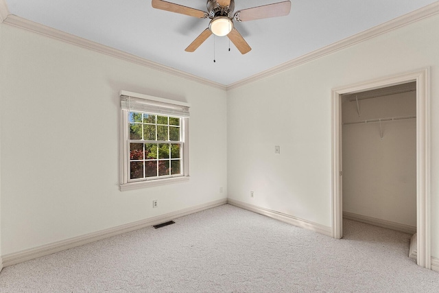 unfurnished bedroom with a closet, ornamental molding, a spacious closet, carpet floors, and baseboards