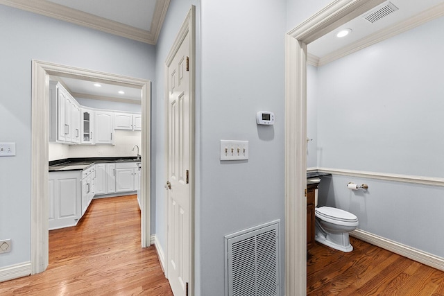 bathroom featuring toilet, crown molding, vanity, and visible vents