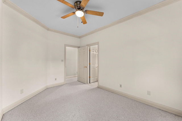 unfurnished room with light colored carpet, crown molding, baseboards, and a ceiling fan