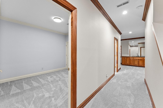 corridor with light colored carpet, ornamental molding, and visible vents