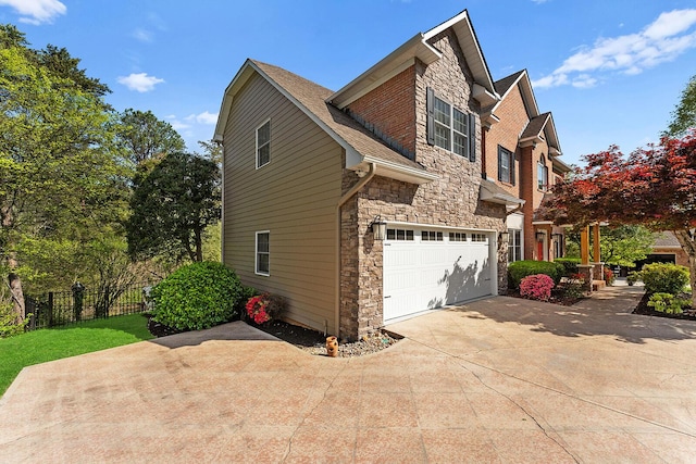 view of side of home featuring stone siding, concrete driveway, fence, and an attached garage