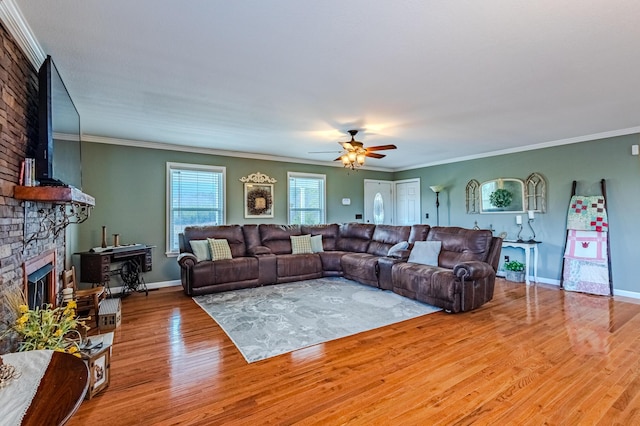 living room with ceiling fan, ornamental molding, a stone fireplace, and wood-type flooring