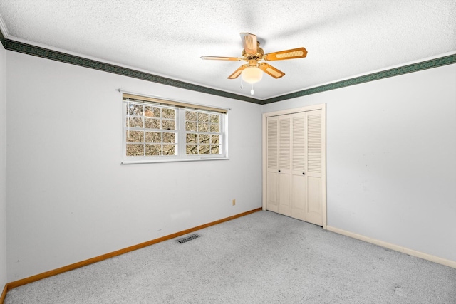 unfurnished bedroom with crown molding, light carpet, a textured ceiling, and a closet