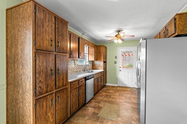 kitchen with sink, ceiling fan, stainless steel appliances, tasteful backsplash, and a textured ceiling