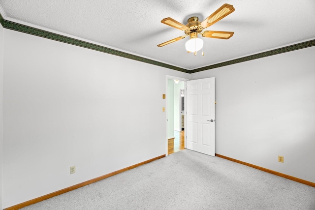 carpeted empty room featuring ornamental molding, ceiling fan, and a textured ceiling