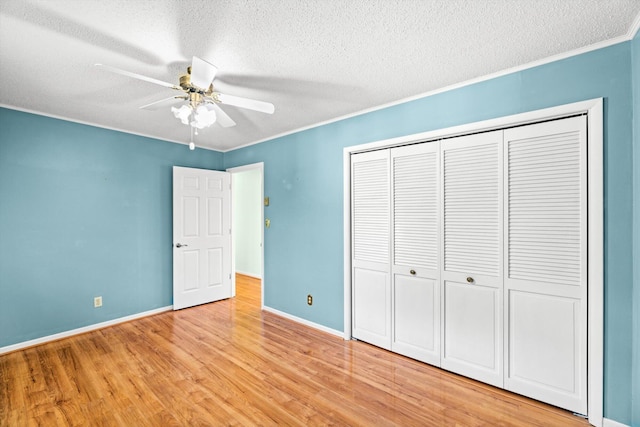 unfurnished bedroom featuring ornamental molding, a closet, a textured ceiling, and light wood-type flooring