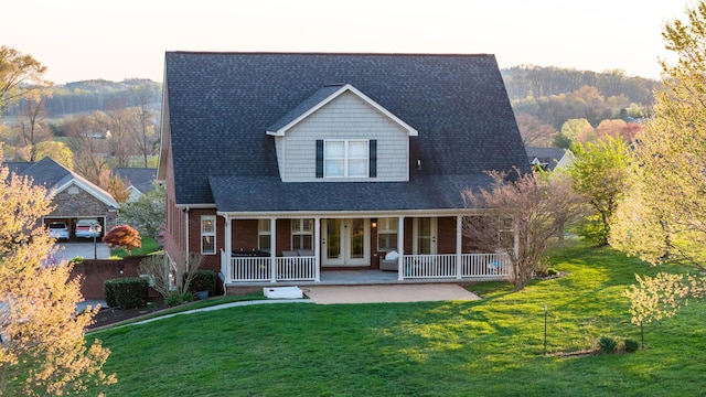 view of front of house with french doors, a front yard, covered porch, and brick siding