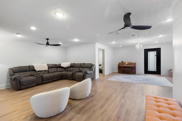 living room featuring light wood-style flooring, ceiling fan with notable chandelier, and baseboards