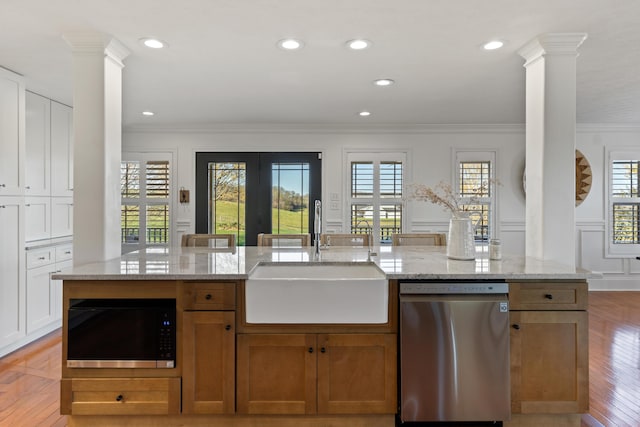 kitchen with decorative columns, a sink, dishwasher, built in microwave, and ornamental molding