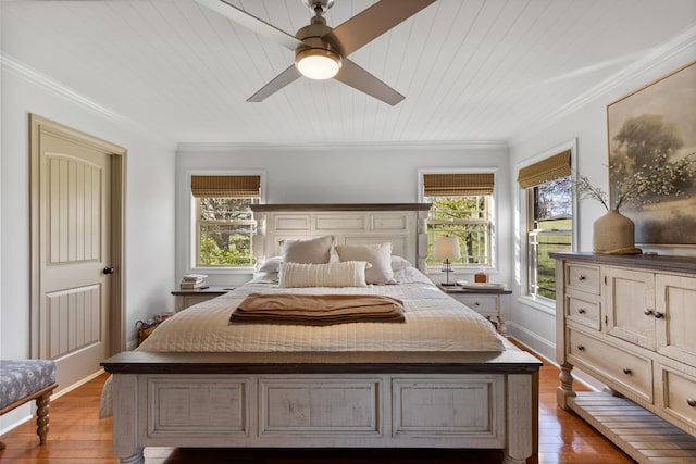 bedroom featuring baseboards, ornamental molding, multiple windows, and hardwood / wood-style flooring