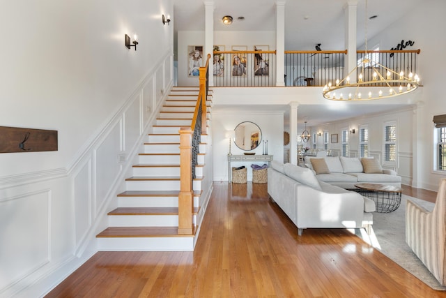 unfurnished living room featuring an inviting chandelier, a decorative wall, hardwood / wood-style floors, and ornate columns