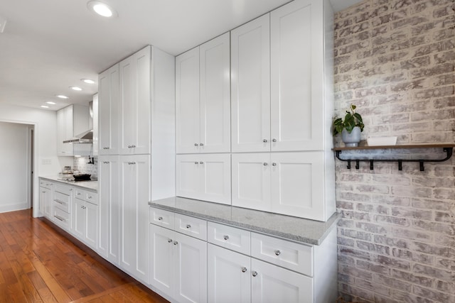 kitchen with stovetop, brick wall, and white cabinets