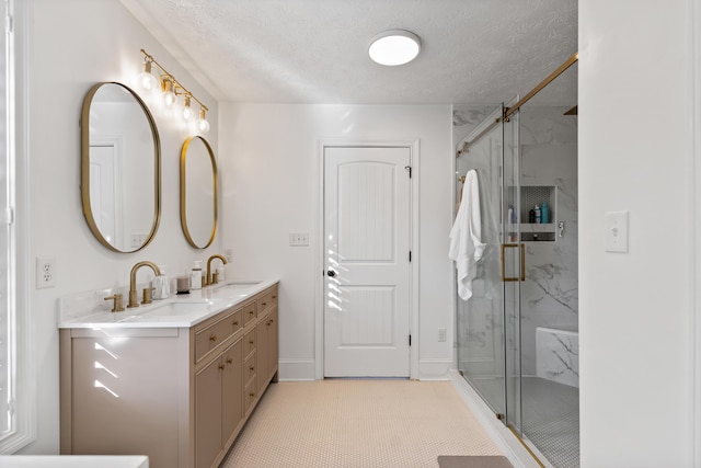 bathroom with a marble finish shower, double vanity, and a sink