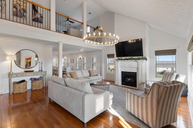 living area featuring a fireplace, high vaulted ceiling, hardwood / wood-style flooring, and a chandelier