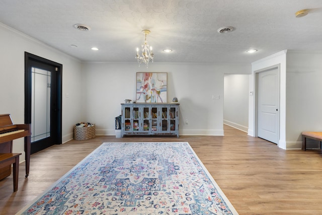 living area featuring light wood-style flooring, visible vents, and an inviting chandelier