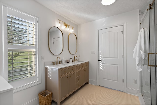bathroom with double vanity, baseboards, a sink, and a textured ceiling