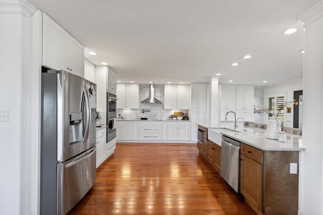 kitchen with white cabinetry, wall chimney exhaust hood, tasteful backsplash, wood-type flooring, and stainless steel appliances