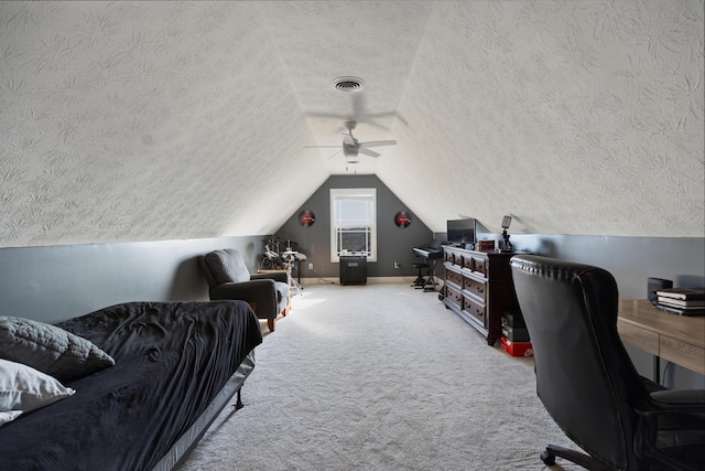 carpeted home office with a textured ceiling, lofted ceiling, baseboards, visible vents, and ceiling fan