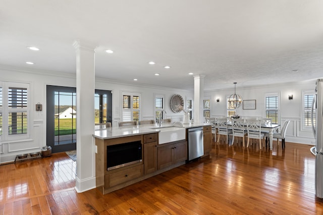 kitchen featuring dark wood finished floors, ornate columns, a sink, and stainless steel appliances