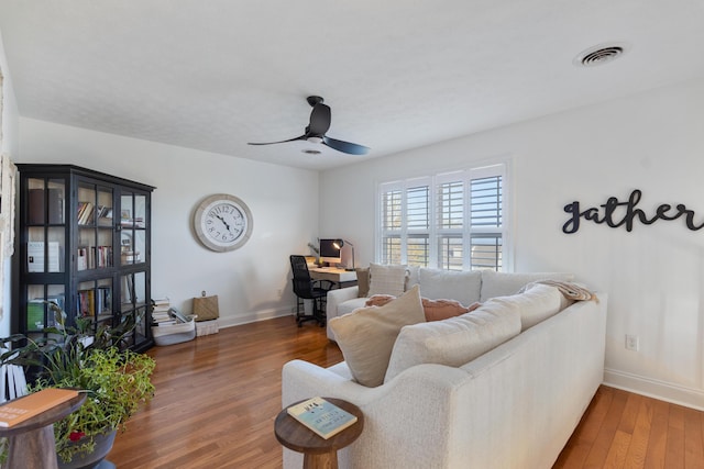 living room with a ceiling fan, wood finished floors, baseboards, and visible vents