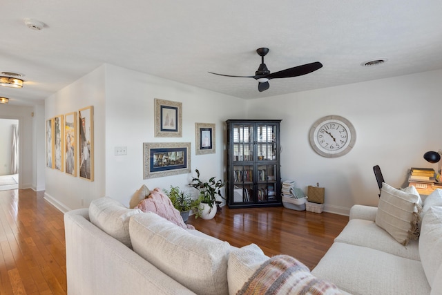 living area with baseboards, ceiling fan, visible vents, and wood-type flooring