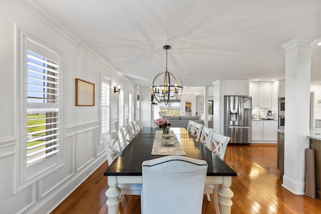 dining room featuring dark wood-style floors, a notable chandelier, a decorative wall, and a healthy amount of sunlight