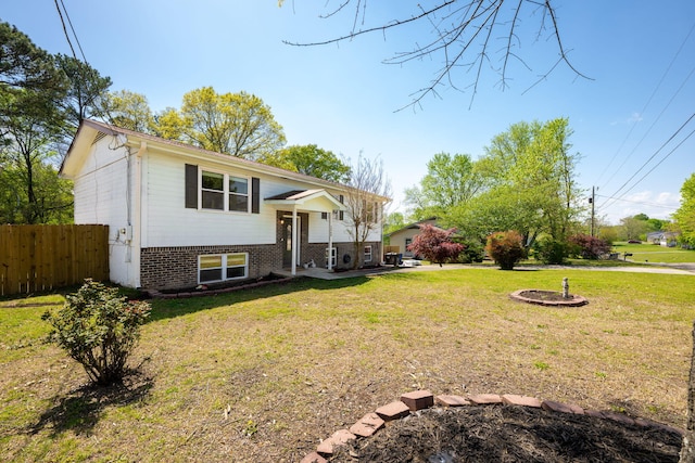 exterior space featuring brick siding, fence, and a yard