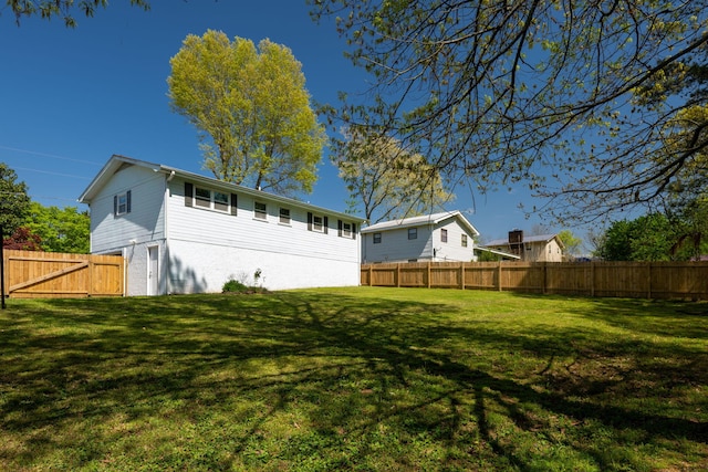 back of house featuring a yard and a fenced backyard