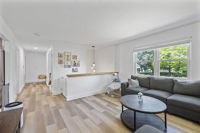 living area featuring attic access, light wood-style floors, and baseboards