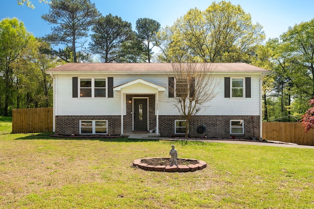 bi-level home with brick siding, a front yard, and fence