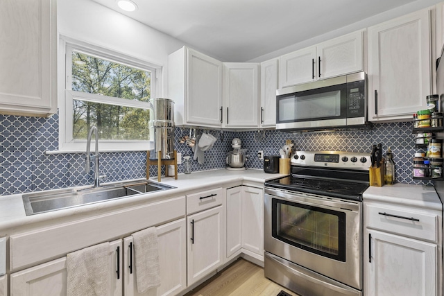 kitchen with light countertops, a sink, white cabinetry, and appliances with stainless steel finishes