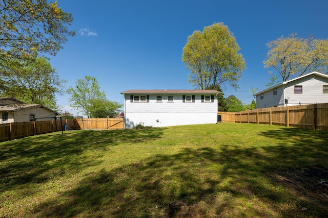 rear view of house featuring a lawn and a fenced backyard
