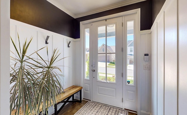 entryway featuring crown molding, a decorative wall, wainscoting, and dark wood-style floors