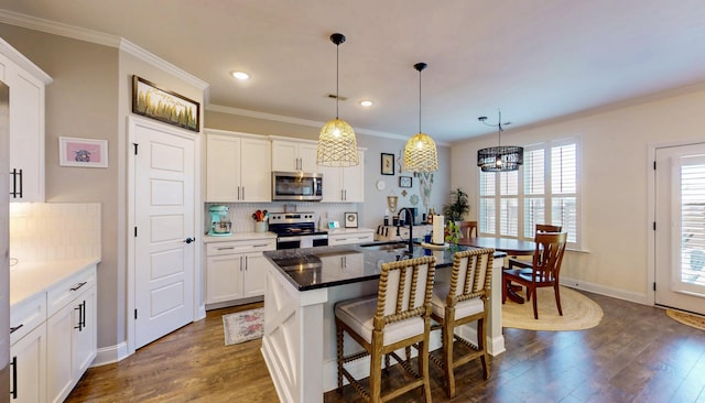 kitchen featuring dark wood-style floors, backsplash, a breakfast bar area, appliances with stainless steel finishes, and a sink