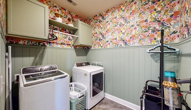 clothes washing area with separate washer and dryer, visible vents, a wainscoted wall, baseboards, and cabinet space