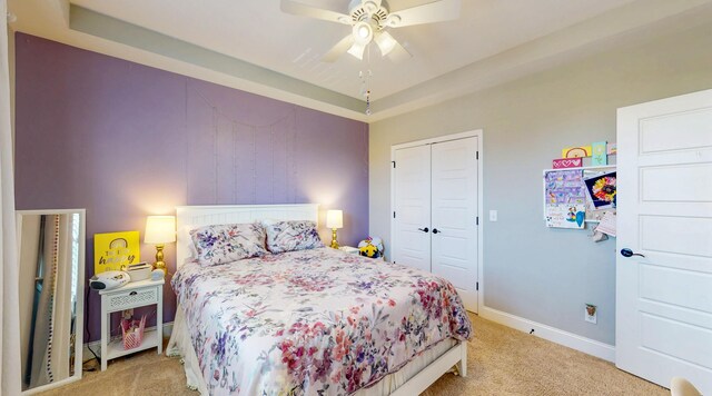 bedroom featuring a closet, baseboards, ceiling fan, and light carpet