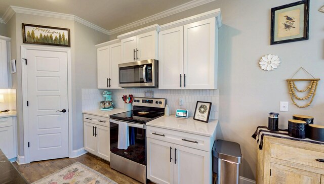 kitchen with tasteful backsplash, light countertops, crown molding, wood finished floors, and stainless steel appliances