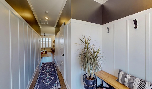 hall with a decorative wall, visible vents, and wood finished floors