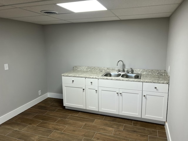 kitchen featuring sink, a drop ceiling, and white cabinets