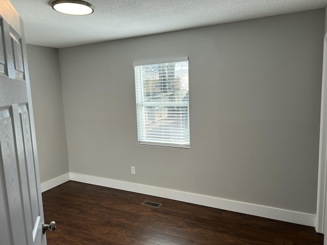 spare room with dark hardwood / wood-style floors and a textured ceiling