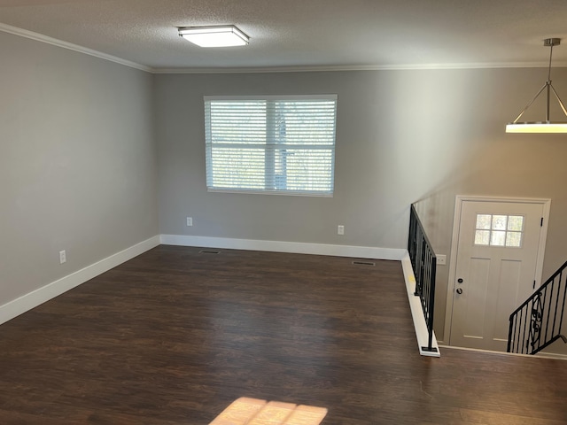 foyer entrance featuring dark wood-type flooring, a textured ceiling, and ornamental molding