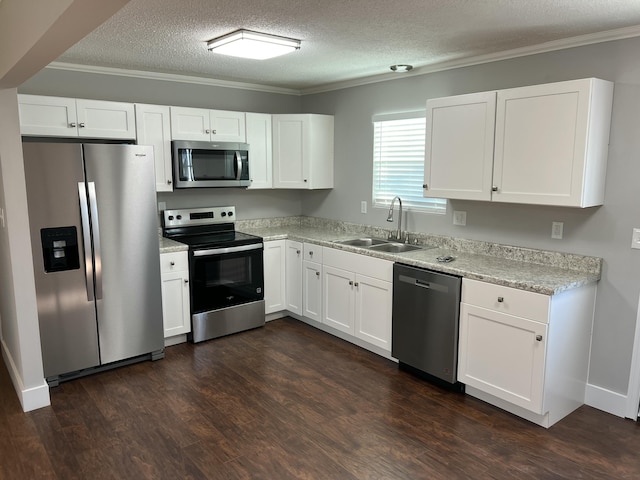 kitchen with stainless steel appliances, ornamental molding, white cabinetry, and sink