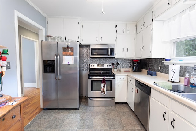 kitchen with light wood-type flooring, tasteful backsplash, ornamental molding, stainless steel appliances, and white cabinetry